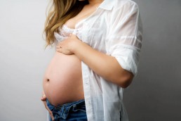 A pregnant woman posing with her hands on her stomach.