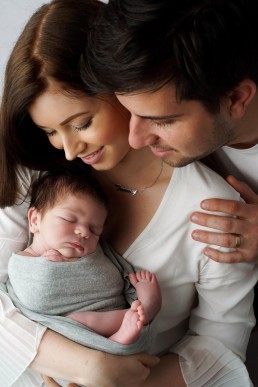 A man and woman are holding a newborn baby in their arms for a photography session in Essex.