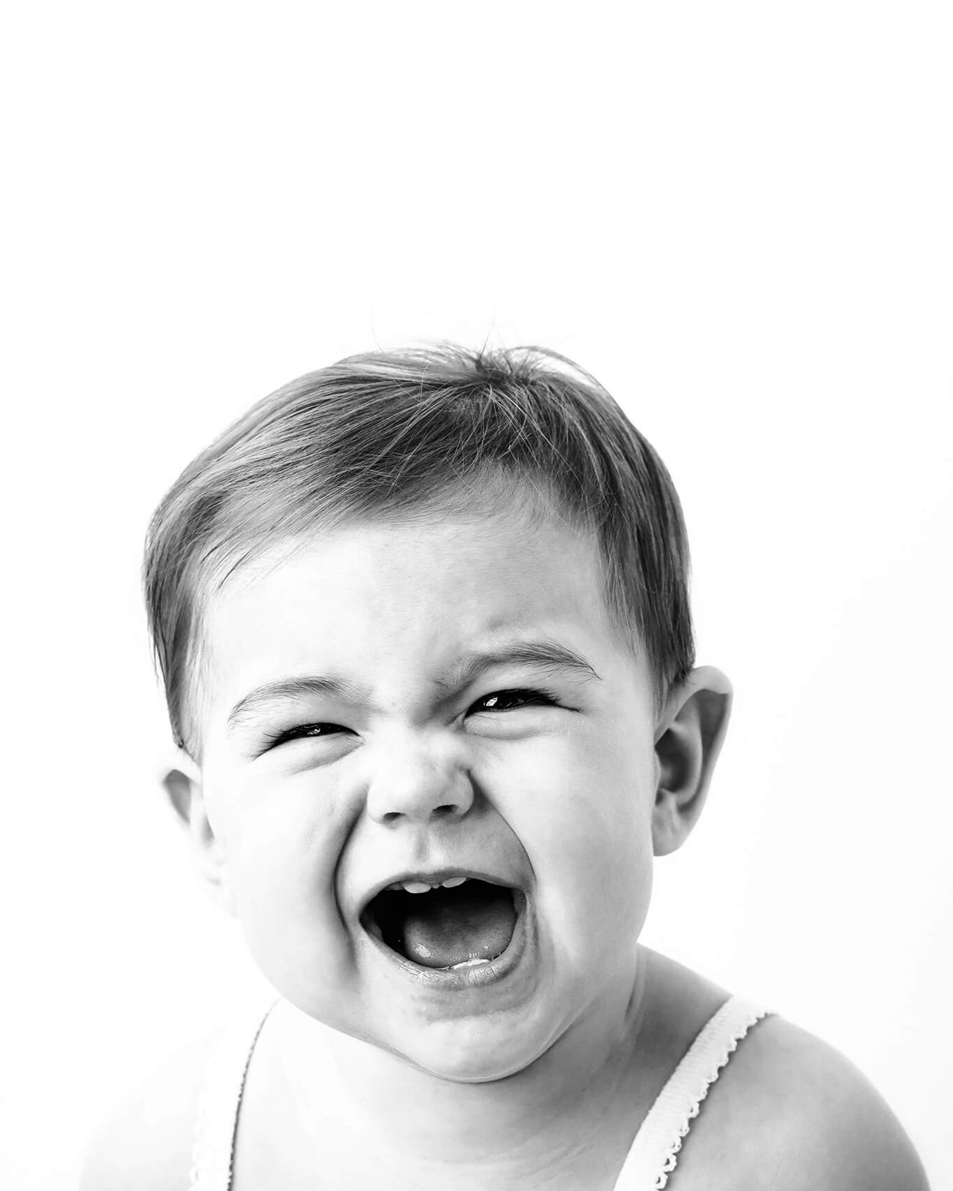 A black and white photo of a baby screaming.