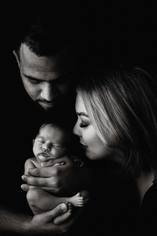 A black and white photo of a man and woman holding a newborn.