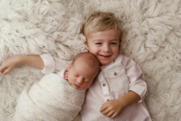 Two newborn boys laying on a white blanket.