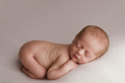 A newborn baby peacefully sleeping on a white blanket in Essex.