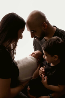A family holding a newborn in front of a white background.