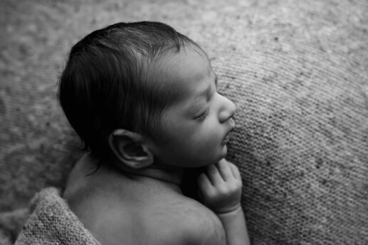 A black and white photo of a baby sleeping on a blanket.