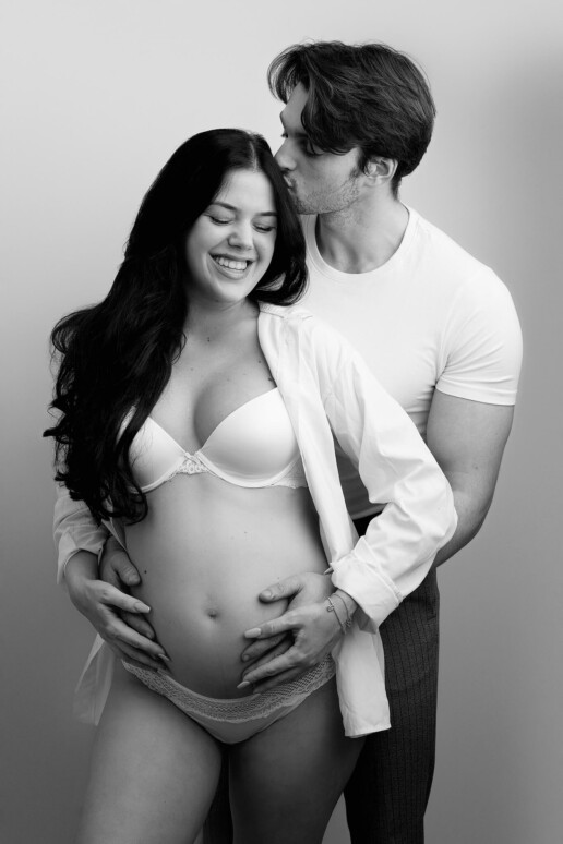 A black and white photo of a pregnant man and woman.