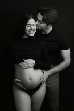 A black and white photo of a pregnant couple.