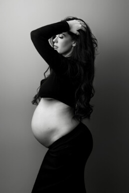 A pregnant woman is posing for a black and white photo.