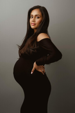 A pregnant woman in a black dress posing for a photo.