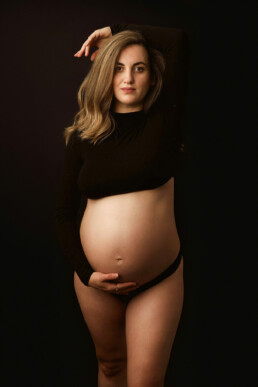 A pregnant woman in a black top posing for a photo.