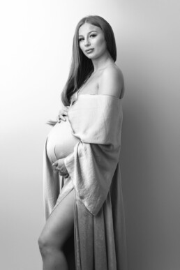 A pregnant woman posing for a black and white photo.