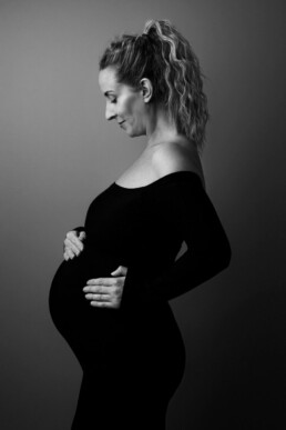 A pregnant woman is posing for a black and white photo.