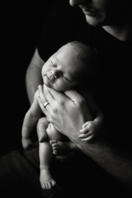 A black and white photo of a man holding a baby.