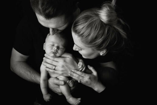 A black and white photo of a man and woman holding a baby.